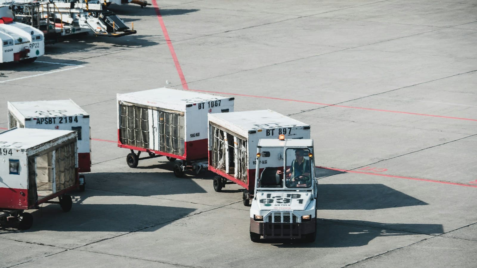 Air cargo containers on dollies being towed across an airport apron